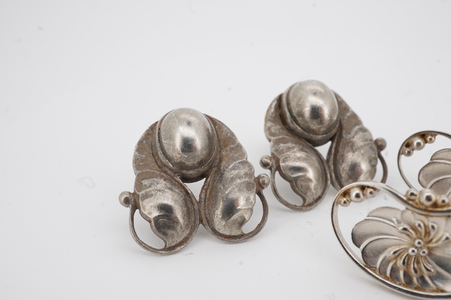 Two pairs of Georg Jensen sterling ear studs, one pair of leaf and berry design, 18mm and flower head form, design no. 52, lacking butterflies.